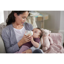 NUK baby bottle held for feeding, clear bottle with soft blue nipple
