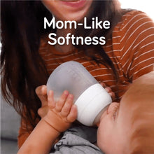 Mother holding a pink-tinted silicone baby bottle while baby drinks
