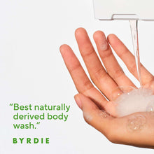 Hand holding lathering soap, with body wash product label text partially visible