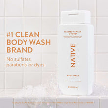 Native body wash bottle, Toasted Vanilla & Honey, beside shower foam and bubbles