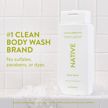Body wash bottle with white pump and surrounding foam bubbles on tile surface