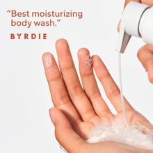 Body wash lather on open hands under a pump, creating white foam.