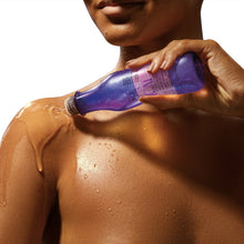 Shower oil bottle being applied to shoulder, purple liquid with droplets