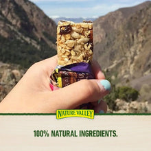 Hand holding Nature Valley chewy trail mix granola bar with whole-grain label