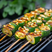 Grilled zucchini halves topped with pine nuts on a charcoal grill