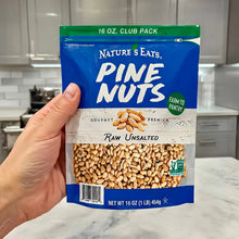 Pine nuts bag held in hand, raw unsalted label