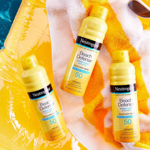 SPF 50 Beach Defense sunscreen spray bottles on towel and skin