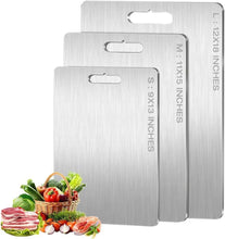 Brushed titanium cutting board set of three with handle holes and size markings, shown with food