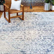 Outdoor area rug with distressed blue geometric medallion pattern on light background