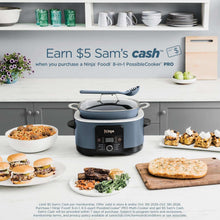 Blue multi-cooker on kitchen counter with lid, surrounded by prepared dishes