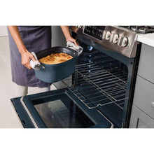 Blue multi-cooker pot being lifted from an open oven door