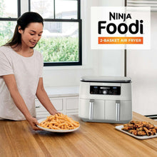 Silver 2-basket air fryer with dual controls, serving fries from basket