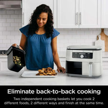 Dual-basket air fryer on counter with basket open and food on plates