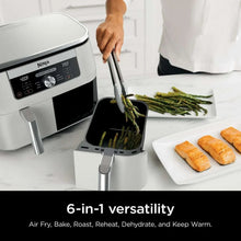 White dual-basket air fryer with basket open and food inside