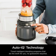 Personal blender base with clear jar and control buttons, shown with hand operating