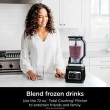 Blender base with clear pitcher filled with purple smoothie and black blending lid