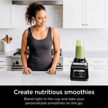 Kitchen blender making green smoothie in a tall cup on the countertop