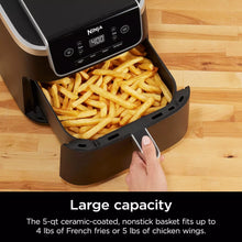 Air fryer with fries in nonstick basket and hand pulling the drawer handle