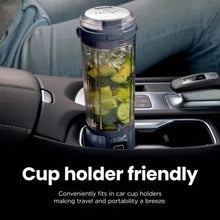 Personal blender in a car cup holder with clear jar filled with blended ingredients