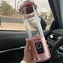 Cordless personal blender held in car, clear 18 oz cup with pink base