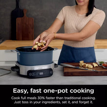Multi-cooker with blue pot; wooden utensil holding cubed vegetables