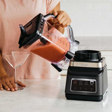 Ninja blender DUO pouring thick orange smoothie from clear pitcher into glass