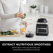Smoothie in a glass jar next to a Ninja blender on a kitchen counter