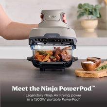 Portable air fryer with open lid, glass cooking basket, and crisped chicken