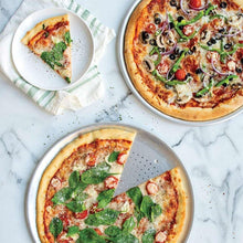 Round pizza pan holding a sliced pepperoni pizza with green pepper and mushroom toppings
