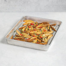 Aluminum roasting pan filled with roasted chicken, vegetables, and herbs, lid not shown