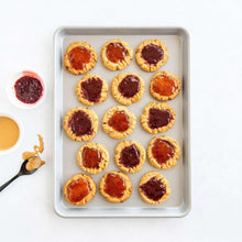 Non-stick baking sheet with white frame holding mini tart cookies