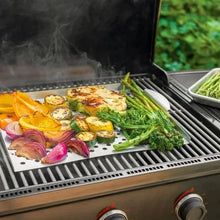 Perforated grilling tray on an outdoor grill with mixed vegetables and onions