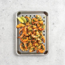 Perforated stainless steel crisping tray with seafood and herb topping