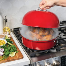 Red kettle smoker on stovetop with chicken inside and domed lid lifted