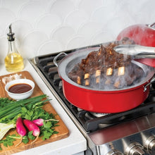 Red kettle smoker on gas range with smoke rising during cooking