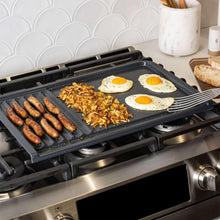 Dual-top grill griddle with grill press, black surface with eggs, sausages, and hash
