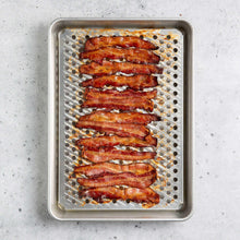 Oven crisping pan filled with bacon slices on a perforated rack