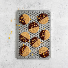 Oven crisping rack tray with cookie and jam halves on perforations