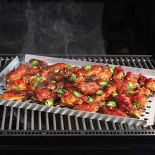 Oven crisping tray on grill with cooked chicken wings and sliced green onions