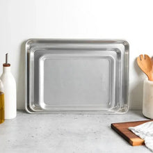 Three-piece baking sheet set with three silver-gray rectangular pans nested