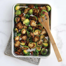 Rectangular aluminum roasting pan with Brussels sprouts and sliced vegetables