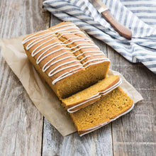 Glazed loaf cake with white icing stripes, sliced pieces on parchment