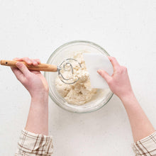 Glass bowl with wooden spoon mixing pale sourdough starter
