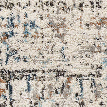 Area rug close-up with speckled ivory pile and scattered blue and charcoal marks.