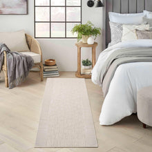 Light beige rectangular area rug with subtle textured pattern and border