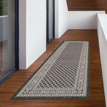 Indoor/outdoor rug with black-and-white geometric border and lattice center.