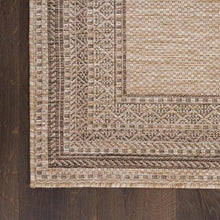 Indoor/outdoor rug edge closeup with braided trim and beige-taupe woven pattern