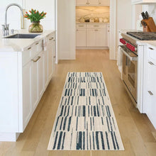 Textured runner rug with cream background and navy-blue stripe pattern in a long rectangular layout.