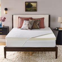 White quilted mattress topper laid over bed mattress, with two-toned edge panel