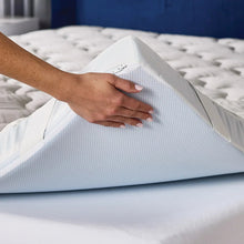 White quilted mattress topper cover being adjusted by hand